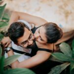 A loving couple embraces amidst lush greenery, captured from above, exuding warmth and affection.